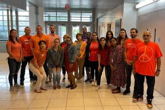 A group of staff members pose together wearing orange