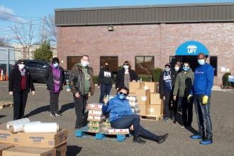 A group of people get together to pack food boxes outside of a union building. 