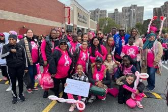 A large group of members wearing pink pose for a photo at a breast cancer awareness walk