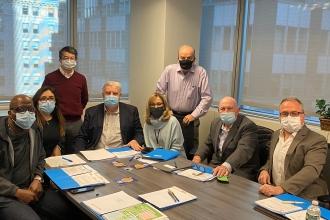 People in a conference room around a table wearing masks