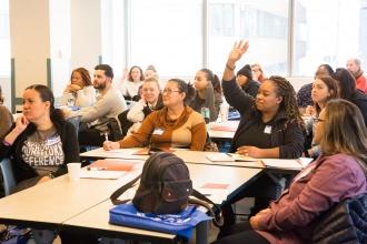 A group of members interact during a session. One member is raising a hand to ask a question. 