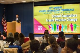 Members listen in as a man speaks at the podium. 