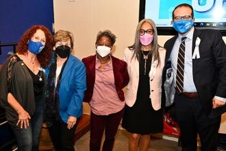Five people pose for a group photo, all masked. 