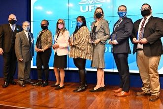 Eight people pose for a group photo, all wearing masks. 