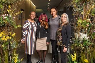 Four women pose for a photo at the entrance of the luncheon
