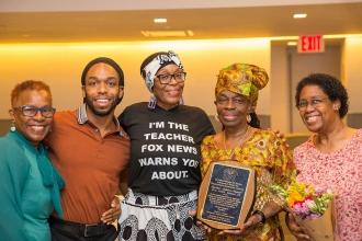 An award winner holding her plaque poses with her family. 
