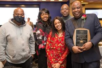 An award winner holding his plaque poses with his family. 
