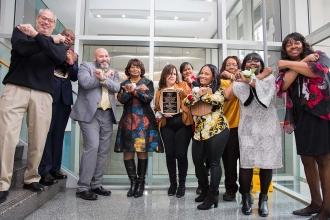 A group of members pose making an "X" with their arms