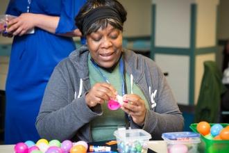 A woman smiles while filling plaster Easter eggs with treats