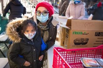 A woman and her daughter pose for a photo. Both are wearing masks. 