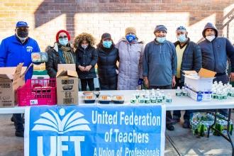 A group poses behind a distribution table with halal food and water bottles. 