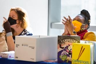 Two women sitting next to each other and laughing in conversation.
