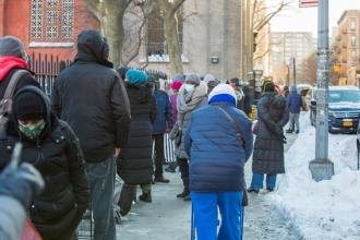 A crowd of people wait on the streets to take part in the food distribution event.