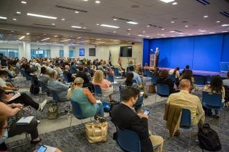 Members in a room watching Mulgrew speak