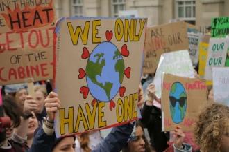 Large crowd of young people holding signs; one reads "We Only Have One" with a picture of the Earth