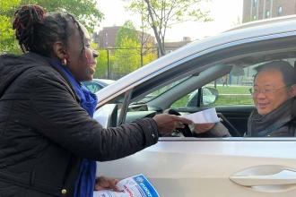 Woman hands out flyers to passing cars