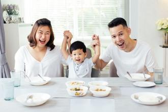 Asian couple with small child smiling with hands up