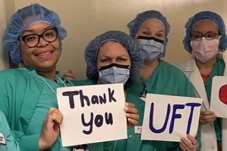 Nurses wearing PPE holding up sign thanking UFT for wrapped lunches