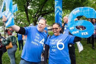 Chapter Leaders Rob Roszkowski of P993Q and Francisca Gachett of P9Q, both District 75 schools, hold up numbers that correspond with their respective pension tiers at the Fix Tier 6 action in Queens on May 6, 2025.