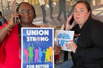 Two women hold up "union strong" and UFT posters while making phone calls.