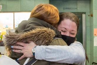 One teacher hugs another