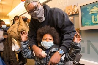 UFT District 9 Representative Aqeel Williams helps a boy try on his new coat. 