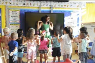 UFT teacher standing with hands on shoulders in classroom in front of kindergarten students