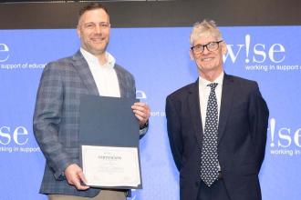 Award-winning teacher Robert Trialonas is congratulated by David Anderson, president and CEO of W!se.