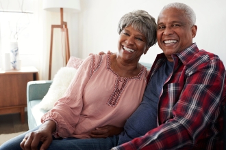 Mature African American Couple sitting on a couch smiling