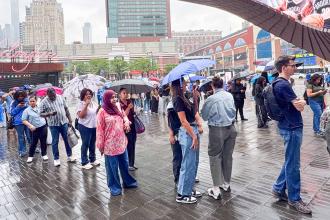Throngs of new teachers hoist umbrellas and brave the rain as they line up to enter Barclays Center.