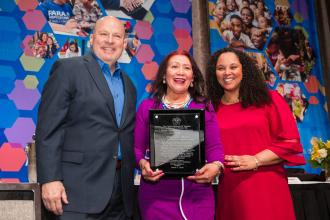 Marizol Rizol (center), the Humanitarian Award recipient, is flanked by UFT President Michael Mulgrew and UFT Paraprofessionals Chapter Chairperson Priscilla Castro at the UFT Paraprofessional Awards Luncheon on March 7, 2026. 