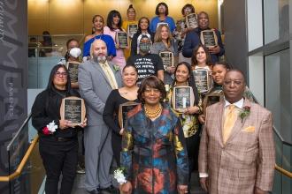 Awardees pose on a stairwell holding up their plaques