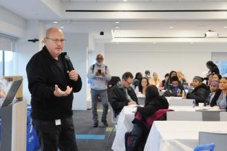A man addresses a group of attendees at a parent conference.