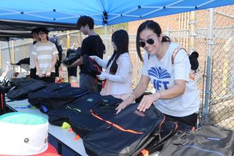 A Staten Island teacher hands out backpacks at the UFT's 5th annual Staten Island Back-to-School BBQ.