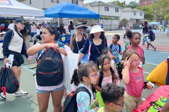 A parent who runs a day care center at a giveaway table with some of her students during the 5th annual UFT Staten Island Back-to-School BBQ. 