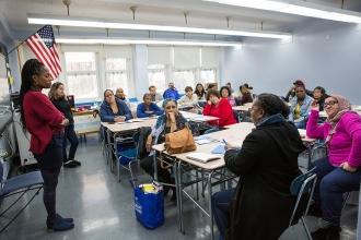 People seated in a classroom with teacher standing