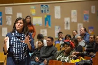 Woman speaks in front of crowd of people seated