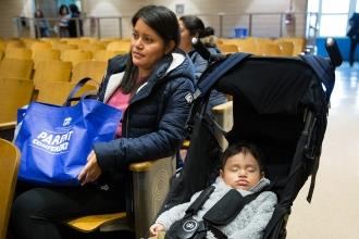 Woman sits in auditorium with sleep child in stroller