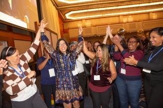 A woman in a blue dress is celebrated by her colleagues as she receives an award. 