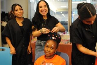 Megan Pomara, a cosmetology teacher at Queens Technical HS, styles a 6-year-old student’s hair.