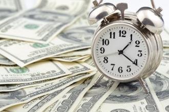 Clock on a surface full of $100 bills