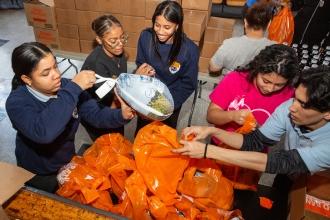 Student and parent volunteers pack bags of food filled with turkey or chicken and all the fixings.