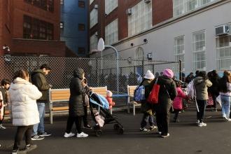  A long line of families wait in the chill in PS 14’s schoolyard after dismissal to get bags of food.
