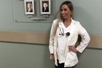 Nurse with stethoscope poses in hall