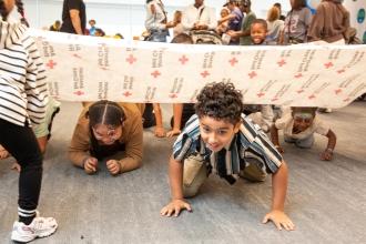 Kids have fun learning as they participate in a drill by UFT partner the Red Cross in how to crawl if they need to escape during a fire at the UFT Bronx KidZone and Community Resource Fair on Oct. 4