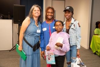 Maria Morales, UFT Bronx parent and community outreach liaison (left), stands with a representative of UFT partner Smile Savers and a parent winner of a raffle prize Angela Gutirrez with her child.