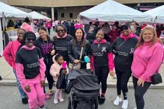 A group of marchers working in the Bronx pose for a group photo during a breast cancer awareness march.