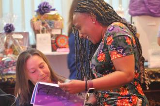Two women look at the event program