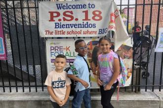 Three young students stand outside a school