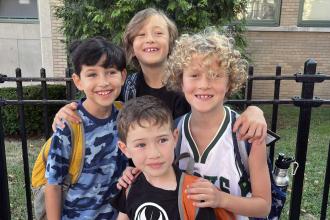Four students stand outside a school building